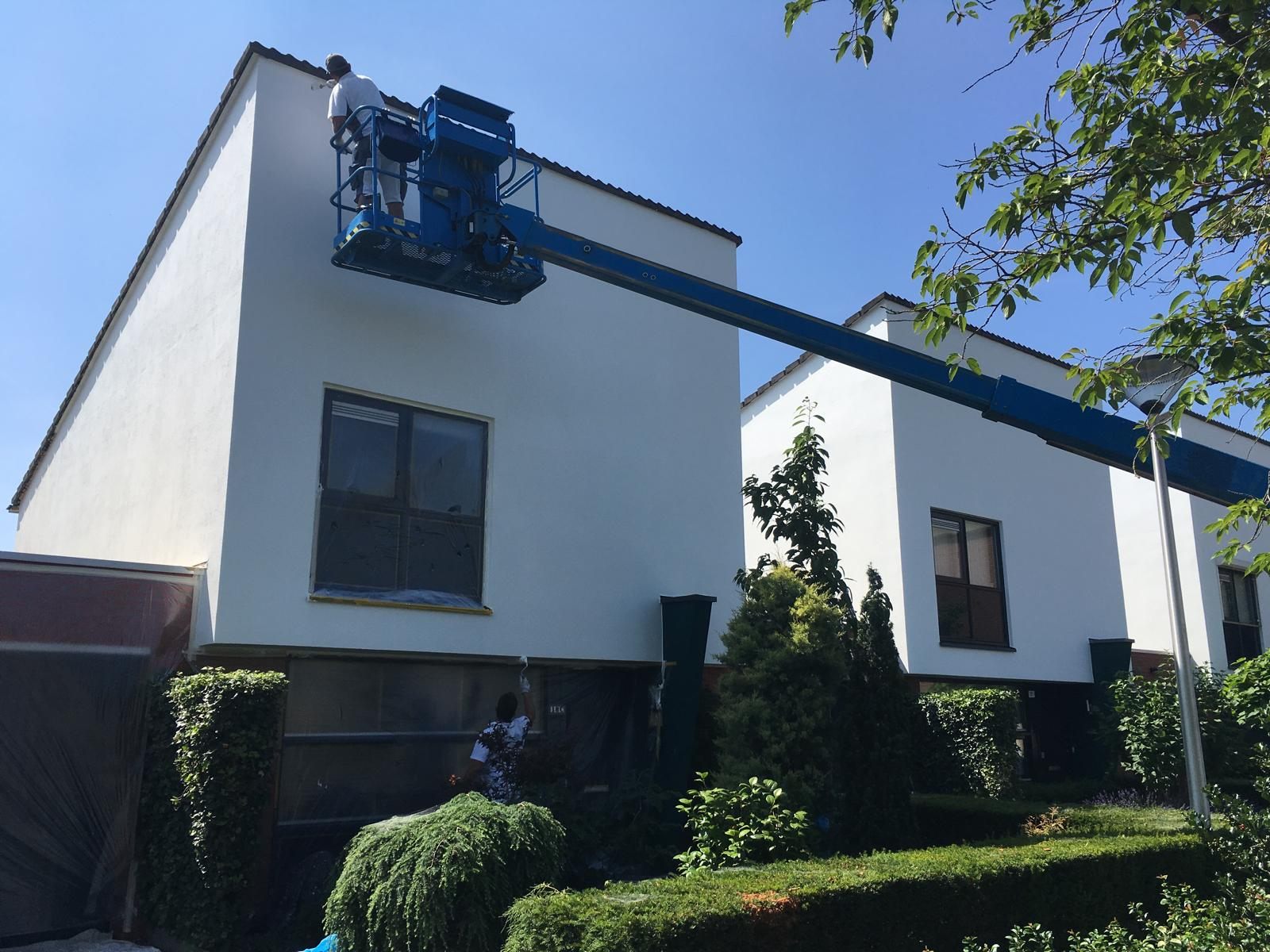 Erwin Kouwenberg schildert vanuit een hoogwerker de bovenrand van een witte gevel in Helmond